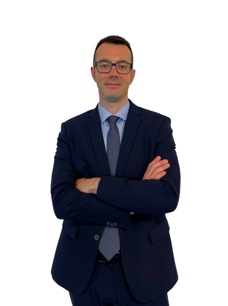 Uomo in abito elegante con braccia incrociate, aspetto professionale e sfondo neutro, in posa come consulente finanziario Fineco.