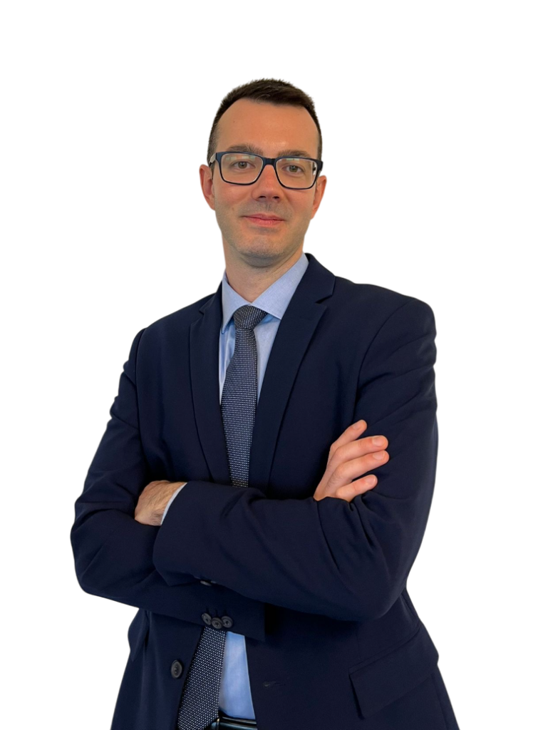 Professionista della consulenza patrimoniale in abito, in posa formale con braccia incrociate su sfondo neutro.